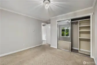 Primary Bedroom: Spacious primary bedroom with mirrored closet doors and built-in shelving. Large windows bring in natural light and offer serene treetop views.