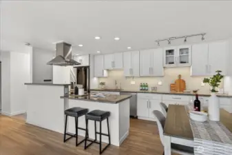 The chef's kitchen impresses with floor-to-ceiling white cabinetry, granite countertops, a classic tile backsplash, and a pro-style stainless steel range hood as the centerpiece. Offering bar seating, stainless steel appliances including a French door refrigerator and dishwasher, under-cabinet lighting,  make this kitchen as functional as it is beautiful. Enjoy the view of Lake Washington while cooking.