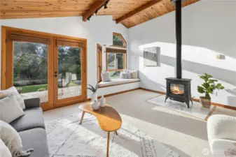 The main living room with a cozy propane fireplace, french doors out to the western facing deck and a cozy sunny window seat.