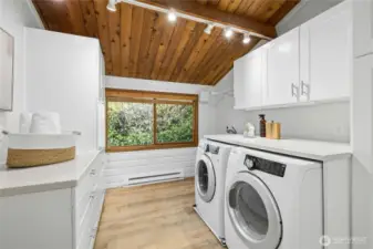 The spacious laundry room with updated cabinetry, solid surface counters, flooring and a handy utility sink.