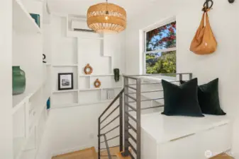The wrap around shelving unit is a work of art that looks over the welded steel railing. One of the mini-splits is part of the design providing warmth in the winter and A/C in the summer. An entry bench with pull out storage is off to the right.