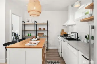 The island features butcher block counters with open storage underneath that adds a nice warmth to the quartz counters on the right.