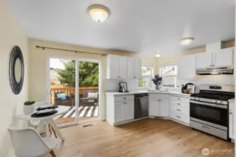 Bright and open kitchen features white cabinets, subway tle backsplash and slider to sunny deck.