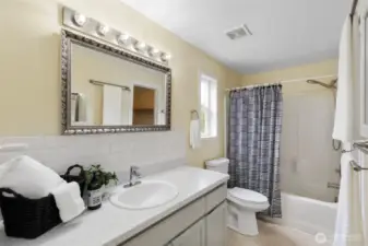 Primary suite bath features large vanity, subway tile backsplash, attractive mirror and light bar.