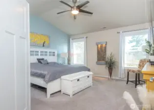 Double doors open to a light-filled primary suite with soaring vaulted ceilings.