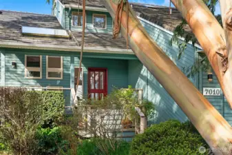 Charming entry with inviting front porch, lush greenery, and architectural character.