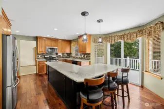 Granite countertops and cherry laminate wood flooring throughout kitchen and living space.