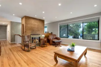 Wood Burning fireplace adorns one wall of the living room. Hardwood floors extend down the hallway of the home.