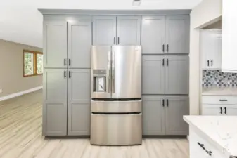 View of cabinets and refrigerator with a peak into living room.
