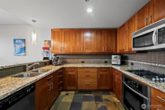 The stylish kitchen features cherry shaker cabinets, granite counters, stainless appliances, and slate tile floors.