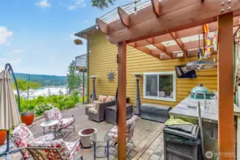 The expansive stone-paved patio features a complete outdoor kitchen, including a built-in BBQ, sink, and refrigerator, perfect for sophisticated alfresco dining. Relax or host guests on the comfortable sectional seating, or enjoy the ambiance created by the overhead pergola and outdoor heater.