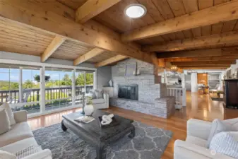 Large living room with statement gas fireplace, skylight and harbor/sound view windows.  Open beam ceilings add a touch of coziness & warmth.  Hardwood floors throughout upper level minus bathrooms & guest bedroom.