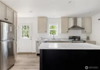 An abundance of cabinets surround the recessed refrigerator.  Back door with steps to back yard