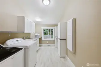 Generous upstairs utility room with built-in ironing board, space to hang clothing and folding station.