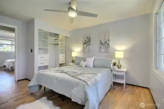 Primary bedroom offers a serene retreat featuring recently refinished hardwood floors, built-in closet storage syteam and overlooks the private backyard.