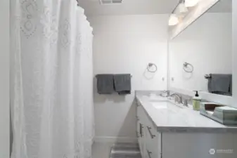 Full bath downstairs with solid surface countertop and tile floors.