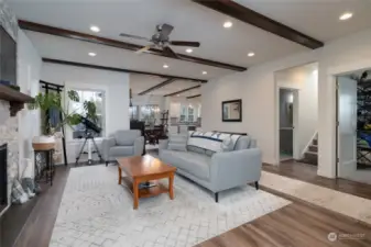 View from entryway into the great room with natural gas fireplace.  Note the beamed detailing on the ceiling.  Dining room and kitchen is to the front of the photo. Bedroom to the right of the photo and 3/4 bath located just before entering the stairs to the second level.