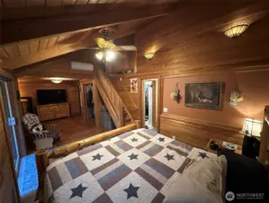 Wide angle shot of the master bedroom with stairs to loft/office and master bathroom with walk-in closet.