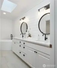 Primary bathroom featuring dual vanity, free-standing soaking tub, double headed shower and a skylight that bathes the space with natural light.