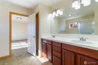 Primary ensuite with double sinks & linen closet behind bathroom door