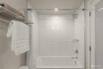 The full bathtub features chrome fixtures and shelving.