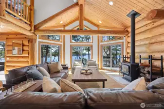 Lodge-inspired great room with panoramic views, dramatic vaults, and a commanding wood stove centerpiece for year-round coastal ambiance and comfort.