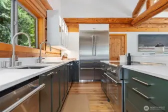 Thoughtfully designed for both form and function, the kitchen features dual sinks, top-tier appliances, and custom cabinetry—all bathed in natural light with sparkling ocean vistas beyond.