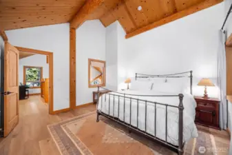 Soaring cedar ceilings and exposed beams highlight the refined craftsmanship of one of two upper level bedrooms. Expansive wall space and peaceful forest views create a calm, luxurious retreat.