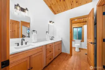 This spa-inspired jack and jill upper level bathroom features a custom dual-sink vanity with sleek matte black fixtures, quartz counters, and clean-lined cabinetry. A private water closet and natural wood finishes elevate the serene design.