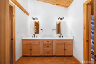 Stylish and spacious, this bathroom offers double sinks, premium fixtures, and timeless design with wood cabinetry and vaulted cedar-clad ceilings.