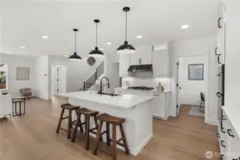 Kitchen View Two: Sleek chef’s kitchen featuring stainless steel appliances, gas cooktop, and designer tile backsplash. The seamless flow to dining and living areas enhances convenience for everyday living and entertaining.  Staged photos are of the model home of the same floorplan within the Foxmoore community and are for visualization purposes only. Colors, finishes, and layout can and will vary.