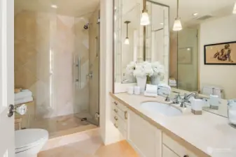 Bathroom with walk-in shower, tile and drawers for storage.