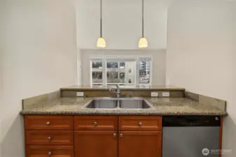 Pendant lights adorn the eat-in bar counter which serves as a connection between kitchen and living room.