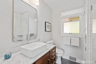 Primary bathroom with shower, updated vanity with marble top and linen closet.