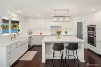 The bright, open-concept kitchen is appointed with professional-grade Thermador appliances, a farmhouse sink, and exquisite custom cabinetry.