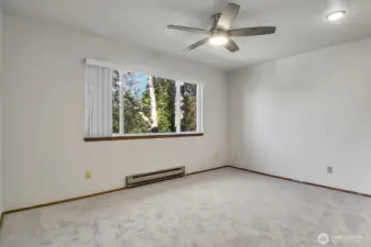 Second bedroom with a large picture window and ceiling fan to circulate the air.