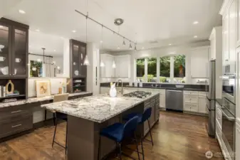 Large, slab island with eating space, prep sink, cabinetry & Dacor gas range