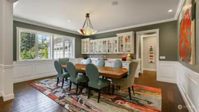 Elegant dining area with wainscot, wall of cabinetry, & large buffet accented by a quartz countertop & art deco chandelier