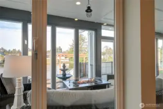 Looking out from the living room, you see into the sunroom, out to the deck, and the water beyond.