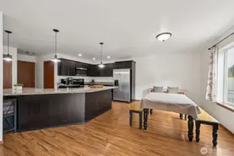 With granite counters for days and a peninsula that doubles as a breakfast bar and conversation hub, this kitchen layout just works. Dark Shaker cabinets give it a grounded, luxe look, and the dining area’s oversized window adds that breath of fresh air we all need.