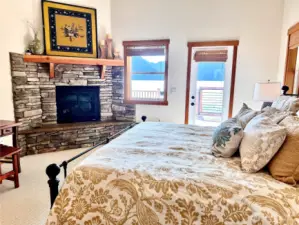 Luxurious primary bedroom w/ stone fireplace.