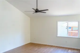 Living room features vaulted ceiling and fan.