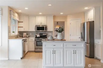 Open kitchen with oversized island and large cabinets for storage. Large pantry next to fridge.