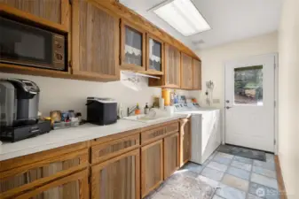 Functional laundry room with abundant custom cabinetry and a guest kitchenette area complete with a coffee bar and microwave.