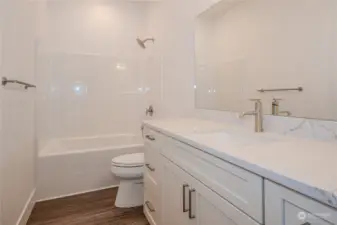 The Full Bathroom in the upstairs hallway boasts excellent storage space, quartz counters, a full bath/shower combo and luxury vinyl plank (LVP) flooring, blending modern style, durability and function.