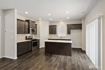 Kitchen offers slab counters, gas range, walk-in pantry and access to backyard via slider door. Colors, finishes, and options will vary.