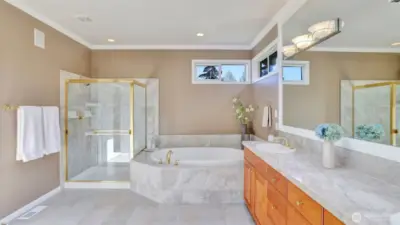 The primary bath continues with marble details, large soaking tub, and separate shower