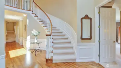 Grand curving staircase leads to more luxury (primary suite entrance on right)