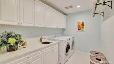 Updated utility room with quartz counter, sink, tile flooring and an abundance of cabinetry.
