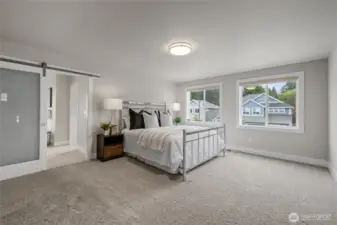 Grand primary suite with double door entry and barn door to bath. Large window in the primary suite fills the room with natural light.